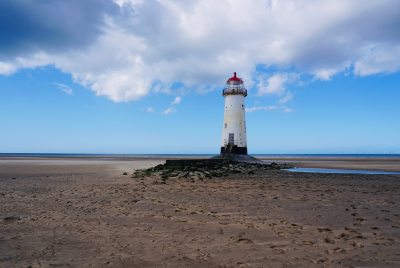 The historic Point of Ayr Lighthouse standing tall against a backdrop of a serene evening sky, marking the northernmost tip of Wales.