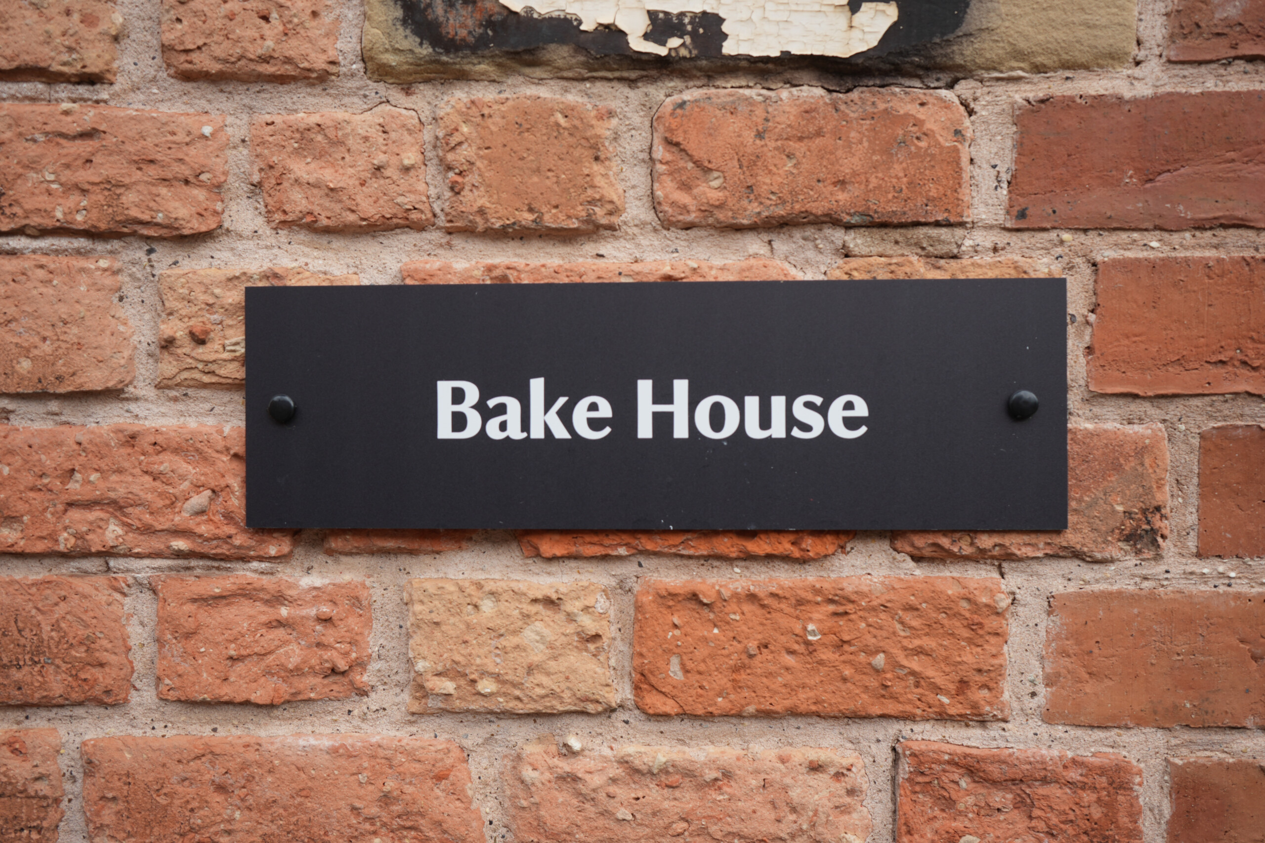 Black Bake House Sign Mounted On Red Brick Wall At The Workhouse Southwell Nottinghamshire England Bake House sign on red brick wall