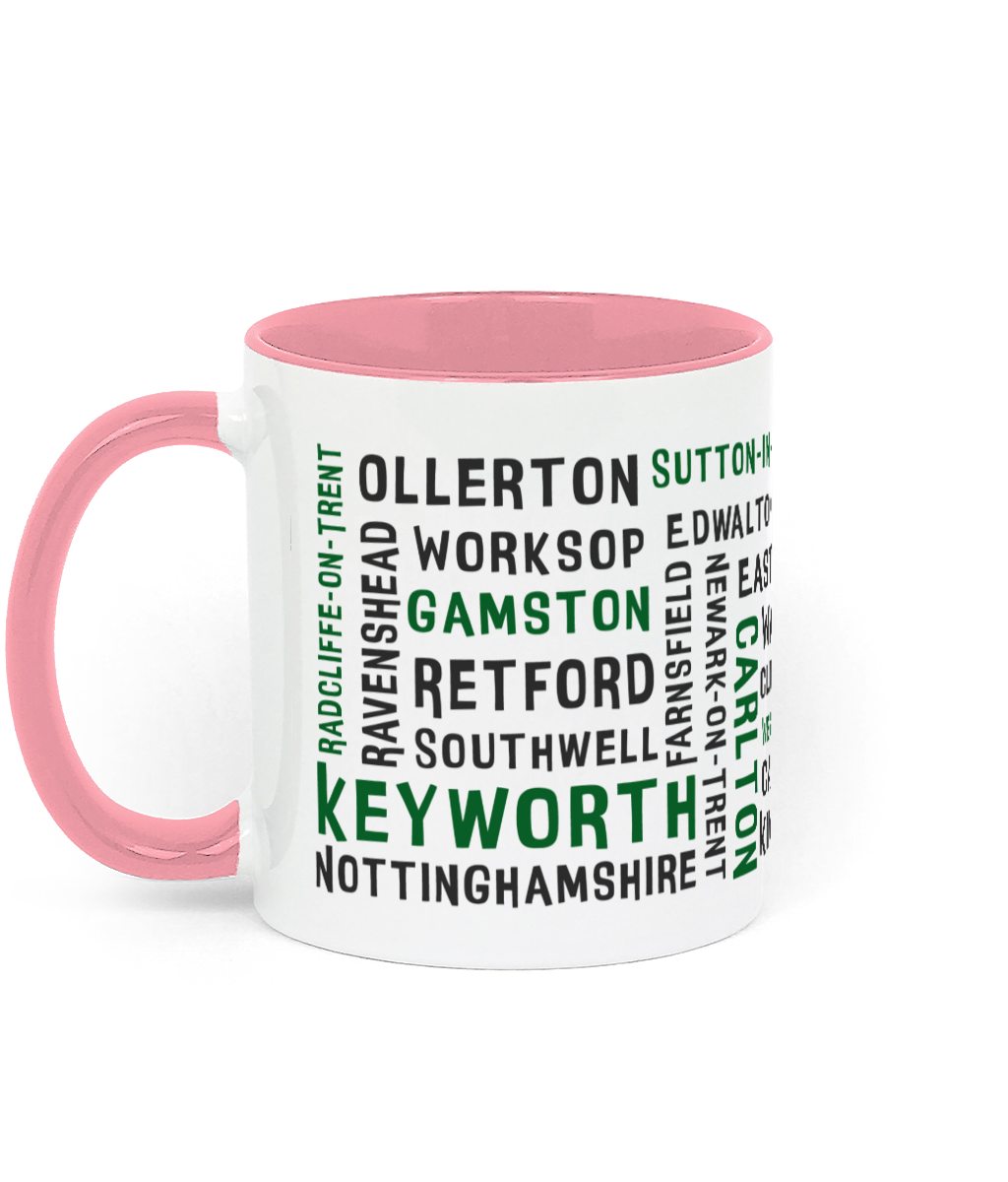 A white ceramic mug with a pink handle and inner, featuring black and green text listing 30 Nottinghamshire places such as Keyworth, Retford, Gamston, Ravenshead, and Southwell. The handle and inner colour can be customised.
